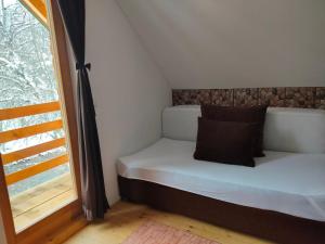 Cama pequeña en habitación con ventana en Vikend kuća Đoković - Jahorina en Pale