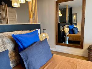 una camera da letto con letto, cuscini blu e specchio di Panorama Suite romantique & Spa a Carcassonne
