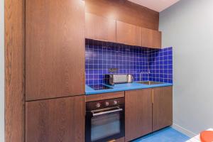 a kitchen with brown cabinets and blue tile at Emblematic apartment 2BR6P Saint honoré Rivoli in Paris