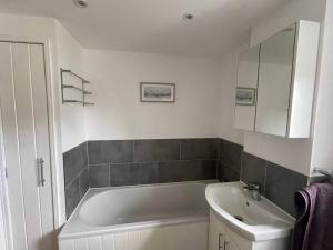 a bathroom with a tub and a sink and a mirror at The Lambing Lodge in Swanton Morley