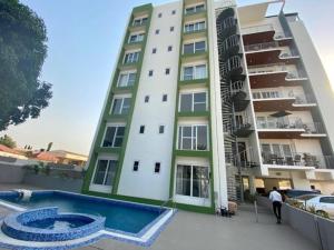 un gran edificio de apartamentos con piscina frente a él en 1 Bedroom Luxury Furnished Apartment in East Legon, en Accra