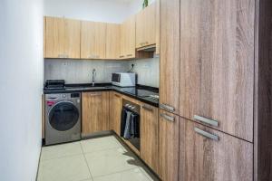 a kitchen with wooden cabinets and a washing machine at 1 Bedroom Luxury Furnished Apartment in East Legon in Accra