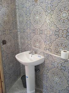 Baño con lavabo blanco y papel pintado en Dar Marwa en Ouzoud