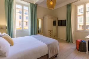 a bedroom with a large bed and two windows at Hotel les Armoiries in Valbonne
