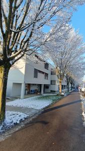 a building with snow covered trees on the side of a street at COSI - Komfortables Privatzimmer mit grosser Terrasse und Parkplatz in Kreuzlingen