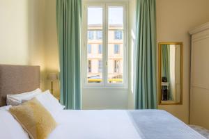 ein Schlafzimmer mit einem weißen Bett und einem Fenster in der Unterkunft Hotel les Armoiries in Valbonne