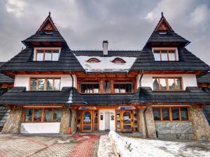a large wooden house with a black roof at Pokoje Gościnne Zbyszko in Zakopane