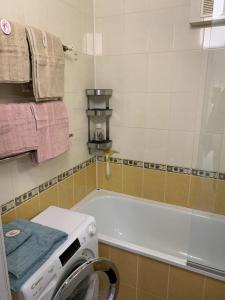 ein Badezimmer mit einer Waschmaschine und einer Badewanne in der Unterkunft Апартаменты LUXURY in Berdychiv
