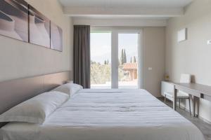 a large white bed in a room with a window at Appartamenti Ceccherini Rosa-Viola in Malcesine