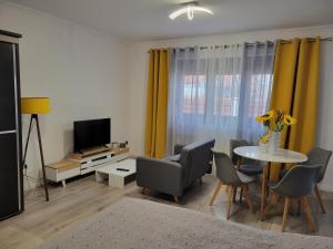 - un salon avec une table, des chaises et une télévision dans l'établissement Concept Urban, à Mediaş