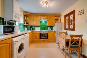 una cocina con armarios de madera y una mesa con lavavajillas en Barley Cottage, en Whittington