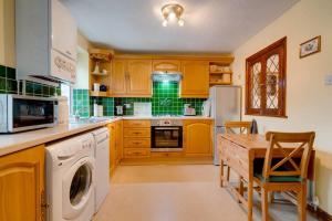 a kitchen with wooden cabinets and a table with a dishwasher at Barley Cottage in Whittington