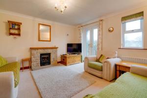 a living room with a fireplace and a tv at Barley Cottage in Whittington