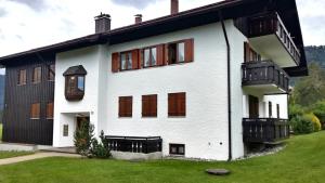 - un bâtiment blanc avec des fenêtres et une cour verdoyante dans l'établissement FeWo "Bergparadies",Oberstaufen-Steibis, à Oberstaufen