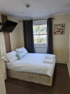 um quarto com uma cama com lençóis brancos e uma janela em Lovely bedroom em Londres
