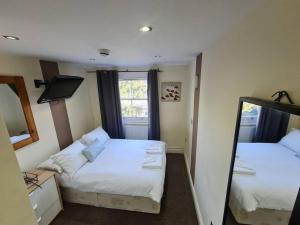 a small room with two beds and a mirror at Lovely bedroom in London