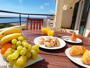 uma mesa de madeira coberta com pratos de comida e fruta em MCStylo-Ocean View no Caniço
