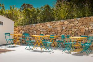 Villa Totò Resort في تشفالو: مجموعة طاولات وكراسي أمام جدار حجري