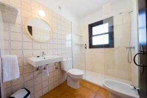 a bathroom with a sink and a toilet and a mirror at Apartamentos Sa Cala in Cala Morell
