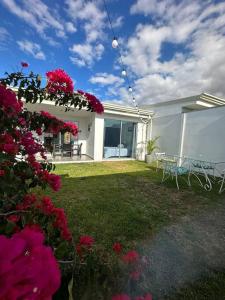 a house with a yard with pink flowers and a table at Casa a 4km del aeropuerto SJO in Santiago Este