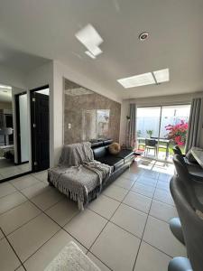 a living room with a black couch in a room at Casa a 4km del aeropuerto SJO in Santiago Este