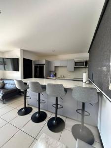 a kitchen with three bar stools and a counter at Casa a 4km del aeropuerto SJO in Santiago Este