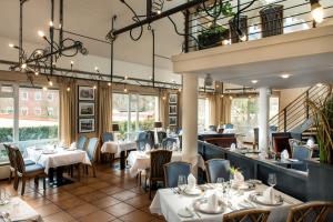 a restaurant with white tables and chairs and windows at Hotel Godewind in Warnemünde