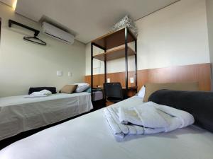 a hotel room with two beds with towels on them at Pousada Jardim do Lago in Cascavel