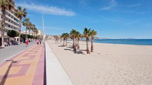 een strand met palmbomen en mensen die erop lopen bij Bungalow con encanto, 100m2, a 800 m de la playa in El Campello