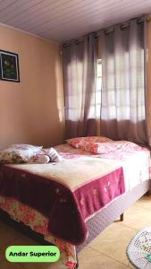 um quarto com uma cama com lençóis cor-de-rosa e uma janela em Hospedaria Recanto dos Pássaros em Morretes