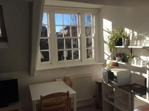 eine Küche mit einer Mikrowelle, einem Tisch und einem Fenster in der Unterkunft Cosy Loft Apartment in Georgian Home in Plymouth