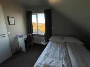 a bedroom with a bed and a desk and a window at Guesthouse Bitra B&B in Selfoss