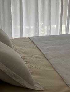 1 cama con sábanas y almohadas blancas frente a una ventana en Amigable departamento en palermo en Buenos Aires