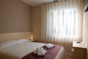 a bedroom with a bed and a window with towels on it at LA PUERTA DE ARZÚA in Arzúa