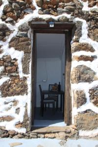 una puerta a un edificio de piedra con una mesa dentro en La Chusmita en Valverde