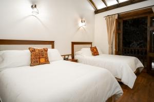 two beds in a room with white sheets at Hotel Casa Alcestre in Villa de Leyva