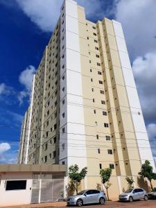 a tall white building with cars parked in front of it at Apt próx. Shopping Pantanal/Centro Político in Cuiabá