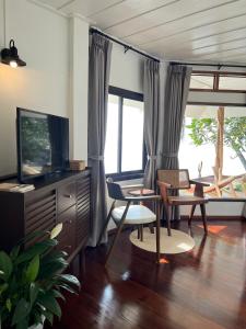 a living room with a tv and chairs and windows at Boon Heritage House Koh Samui in Koh Samui 