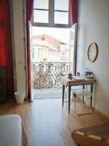 Zimmer mit einem Tisch und einer Tür zu einem Balkon in der Unterkunft Sir Manuel Guest House - Unidade Centro Histórico in Braga