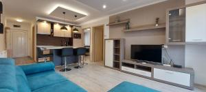 a living room with a blue couch and a kitchen at Laguna Beach Apartmanok in Siófok
