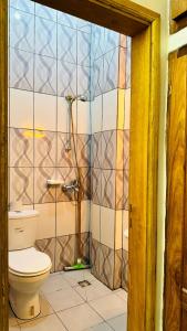 a bathroom with a toilet and a tiled wall at Chambre meublée Biyem Assi TKC in Yaoundé