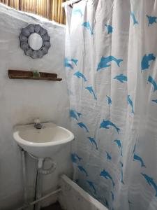 a bathroom with a sink and a shower curtain with dolphins at Casa surf arrels in Montañita