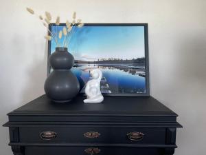 uma cómoda preta com um vaso e uma imagem sobre ele em Utterbyn/Sirsjön 