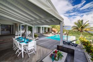 a patio with a table and chairs and a swimming pool at Villa Estheria in Sainte-Anne