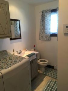 a bathroom with a sink and a toilet and a window at La petite maison du voisin in Mont-Carmel
