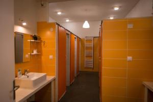 baño con paredes de color naranja, lavabo y espejo en The Holy Rock - Hostel at meteora en Kalambaka