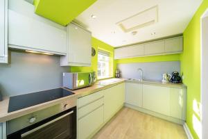 uma cozinha com armários brancos e paredes verdes em Blindwelleyes Cottage em Blairgowrie
