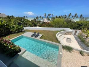 una piscina en un patio con el océano en el fondo en OceanView Villa Manzini with Private Pool ZanzibarHouses en Kiwengwa