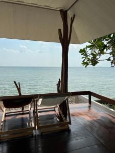 een tafel en stoelen op een balkon met uitzicht op de oceaan bij Boon Heritage House Koh Samui in Koh Samui 