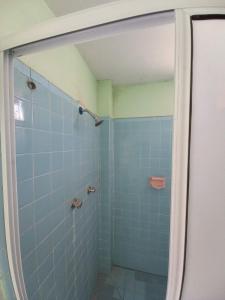 y baño con ducha de azulejos azules. en Casa El Colibrí CEC, en Tehuacán